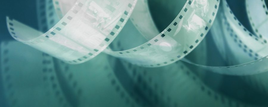 香港电影黄金时代的老式戏院外墙贴满电影海报，霓虹灯光映照下的街景展现1990年代港片繁盛氛围，与玉蒲团影视改编的历史背景相呼应